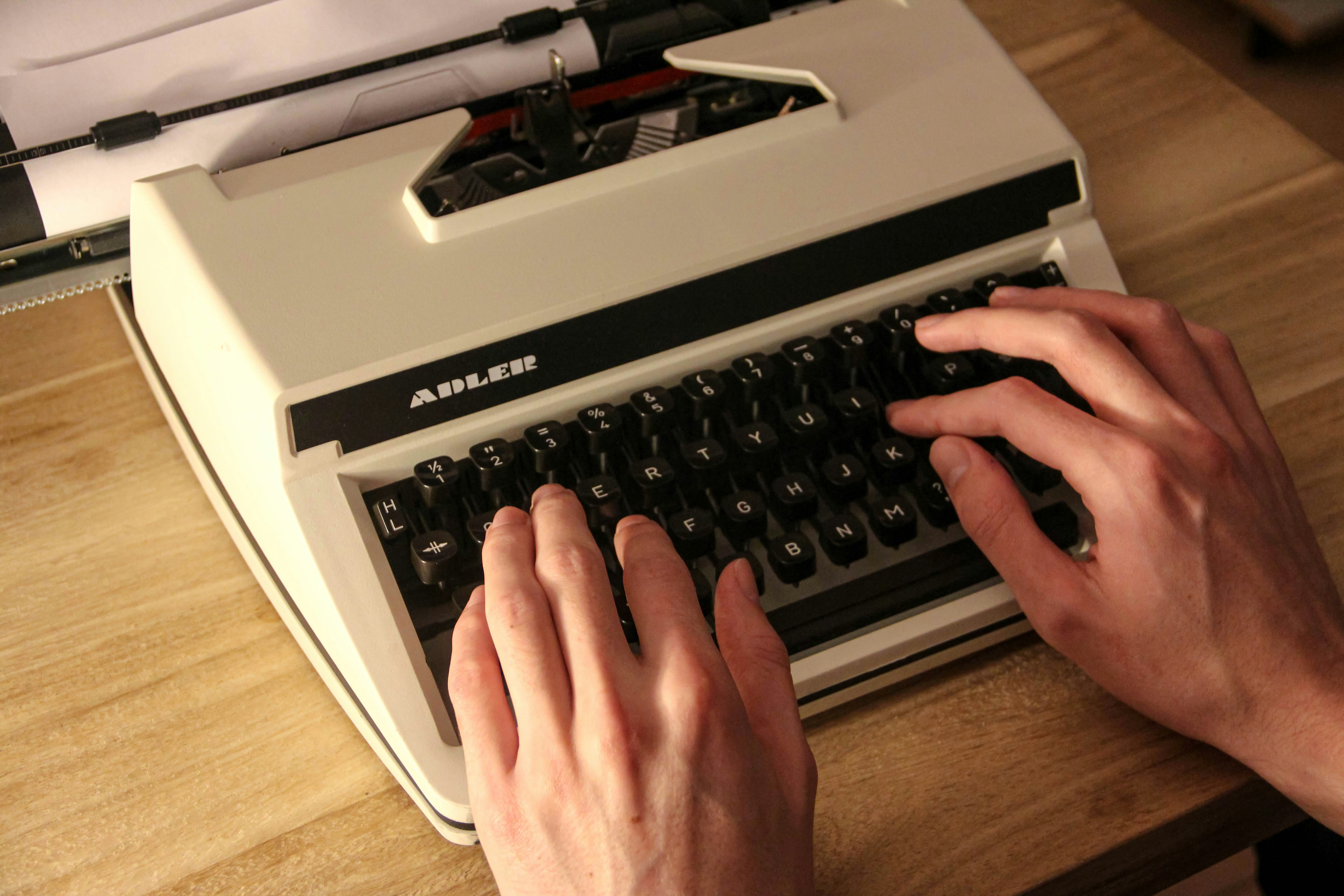 person holding gray and black typewriter